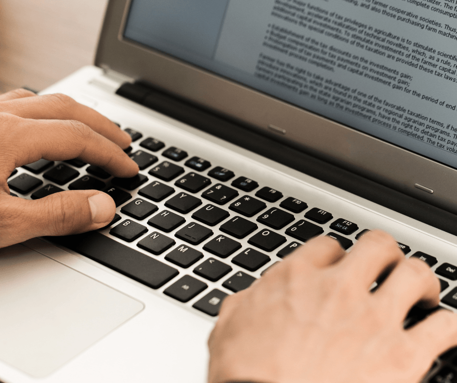 mains tapant sur un ordinateur portable pour la révision d’un texte