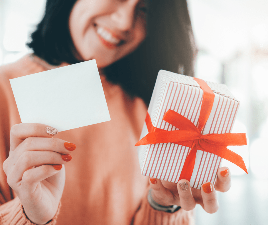 femme souriante tenant une carte-cadeau et un petit cadeau emballé